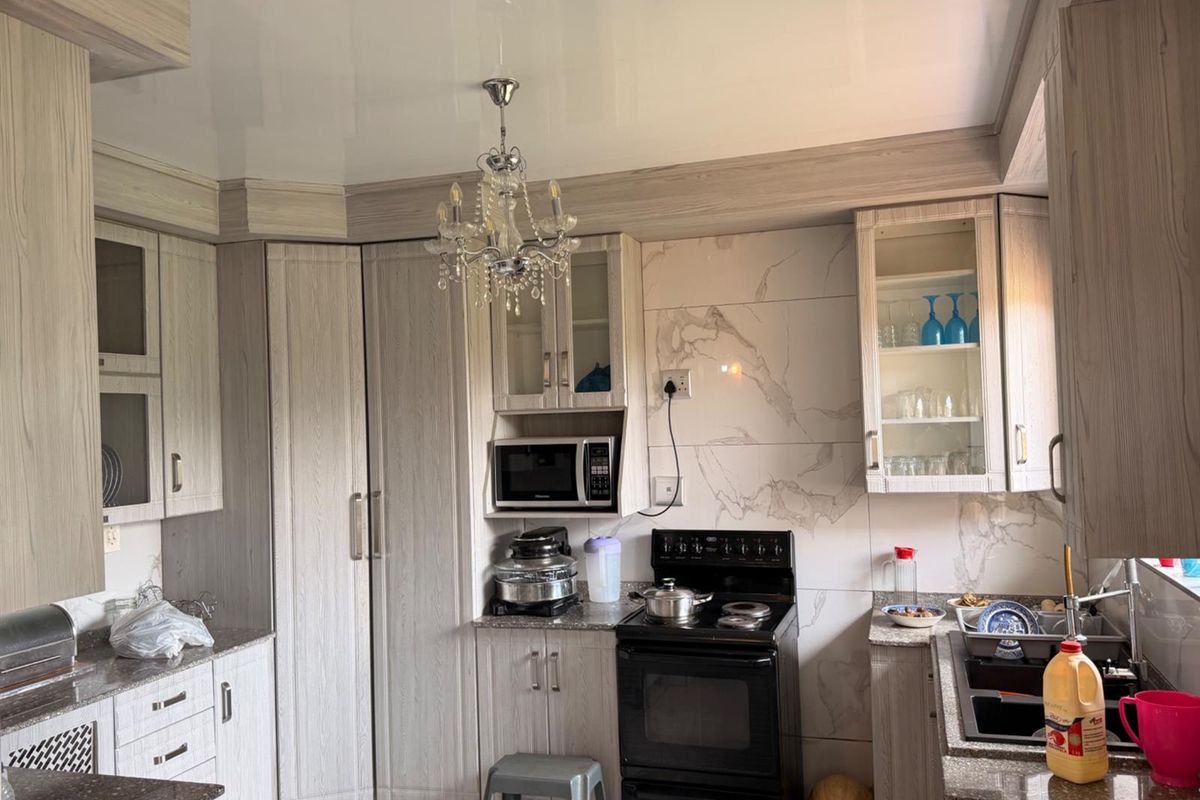 Modern kitchen featuring light wood-grain cabinetry, marble-effect wall tiling, a built-in microwave, and a freestanding oven.
