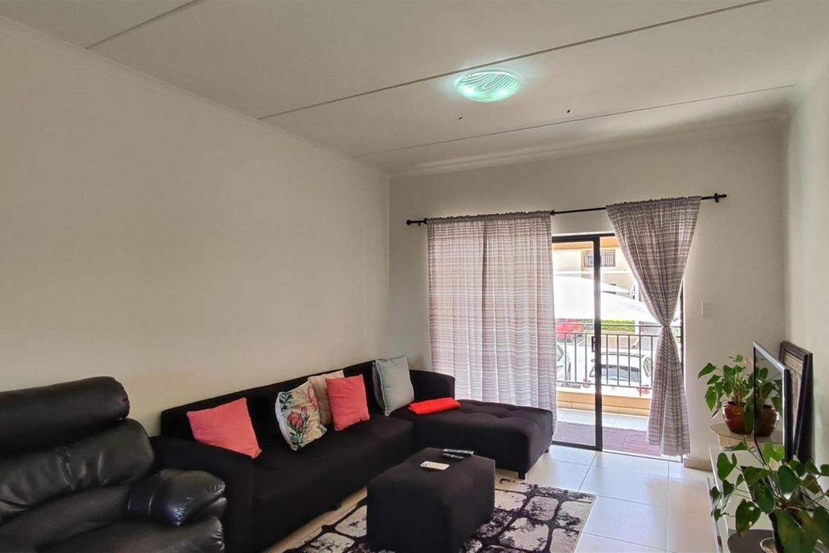 A bright living room featuring tiled flooring and a sliding glass door that provides direct access to an outdoor balcony area.