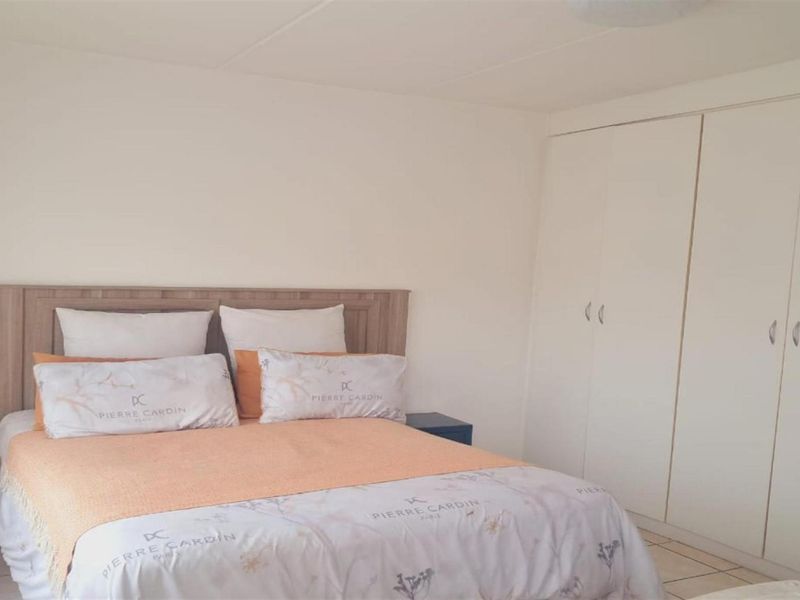A functional bedroom featuring neutral walls, tiled flooring, and ample built-in cupboard storage space.