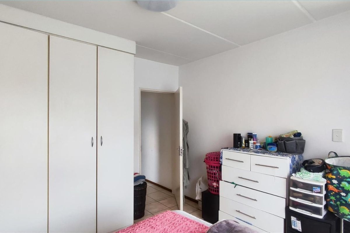 A bedroom featuring built-in wardrobes and tiled flooring, offering a functional space with neutral finishes.