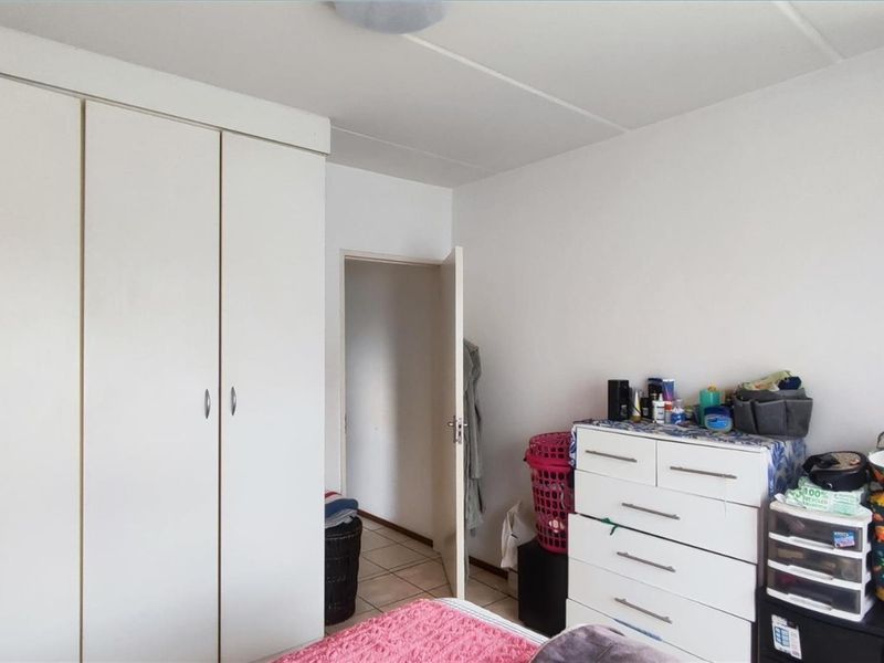 A bedroom featuring built-in wardrobes and tiled flooring, offering a functional space with neutral finishes.
