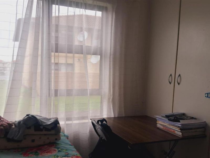 A bedroom featuring a built-in wardrobe and a window with natural light, providing a functional space for rest or study.