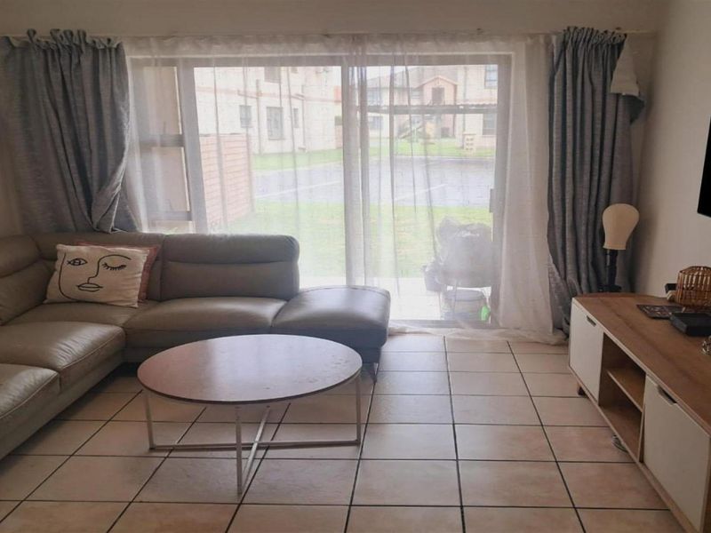 A living room featuring ceramic floor tiles and a large sliding glass door providing access to the exterior.