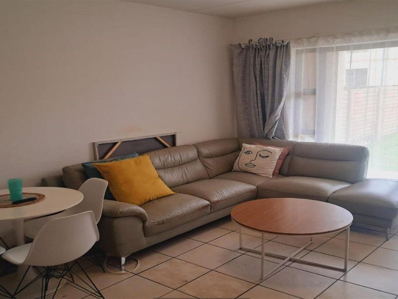 A living room area featuring tiled flooring and a sliding glass door providing natural light.