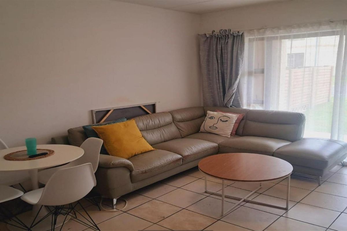 A living room area featuring tiled flooring and a sliding glass door providing natural light.