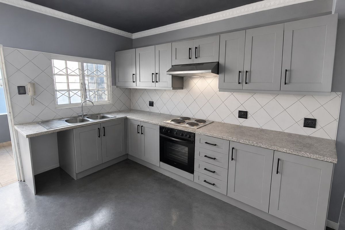 Modern kitchen featuring grey shaker-style cabinetry, granite-look countertops, built-in oven and hob, and polished concrete flooring with a clean tiled backsplash.