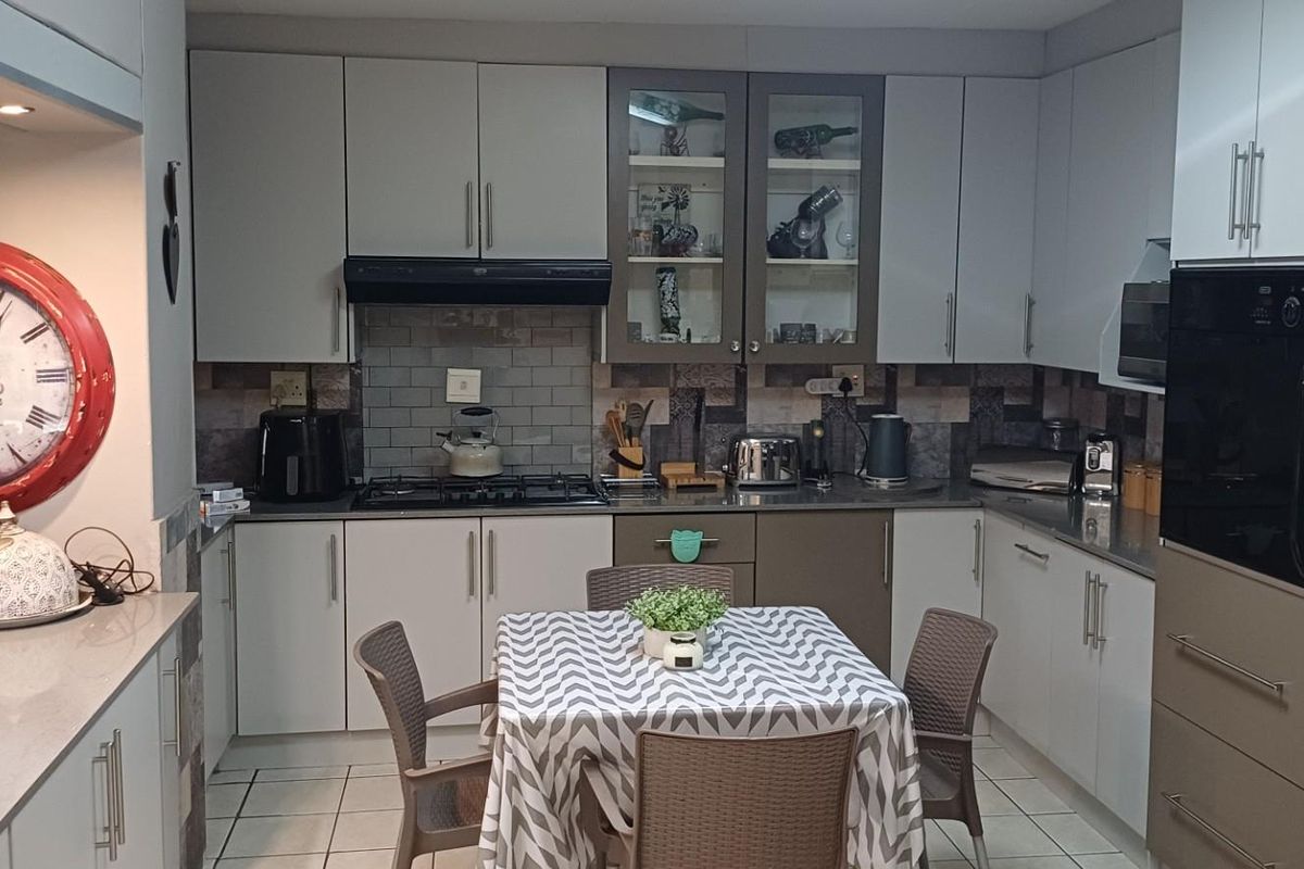 A functional kitchen featuring built-in cabinetry, a gas hob with extractor fan, integrated oven, and tiled splashbacks with a breakfast counter area.
