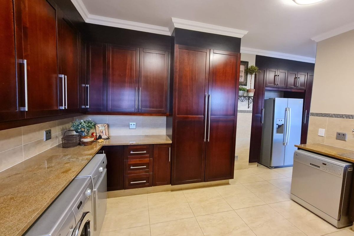 A spacious kitchen featuring dark wood cabinetry, granite countertops, tiled flooring, and integrated appliance spaces.