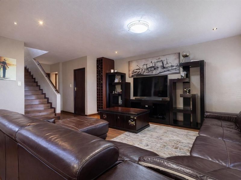 Spacious living room featuring a built-in wine rack, wooden staircase, and recessed lighting, creating a warm and functional family entertainment area.