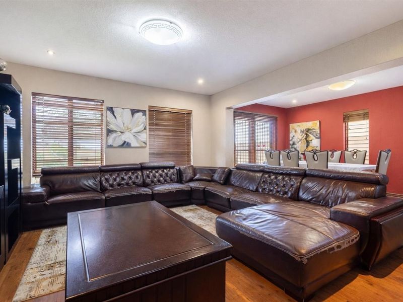 Spacious open-plan living and dining area featuring warm wood-look flooring, recessed lighting, and large windows with fitted blinds.
