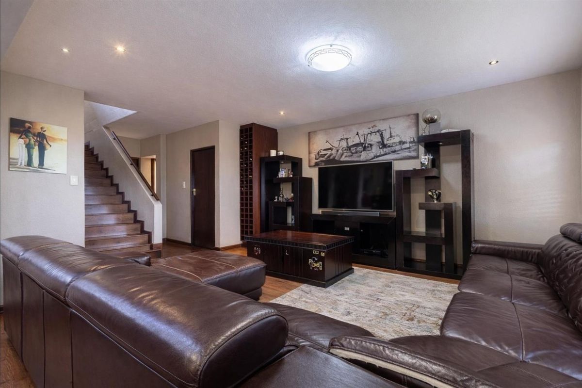Spacious living room featuring a built-in wine rack, wooden staircase, and recessed lighting, creating a warm and functional family entertainment area.