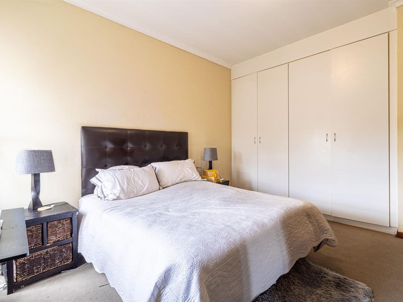 A bedroom featuring built-in floor-to-ceiling wardrobes and neutral wall finishes, providing a functional and practical sleeping space.