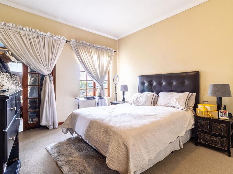 A bedroom featuring timber-framed glass doors leading to an outdoor area and a window with natural light.