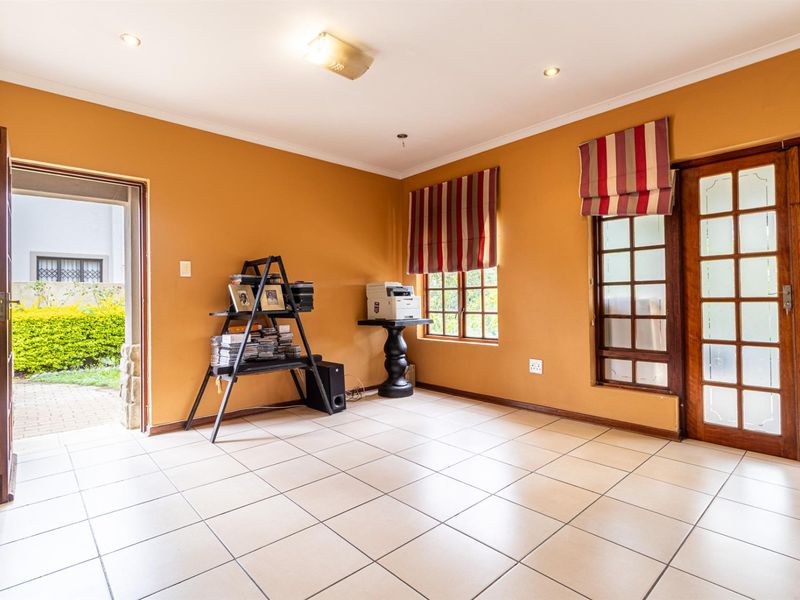 A bright living area featuring tiled flooring, recessed lighting, and direct access to the garden through a glass-paneled door.