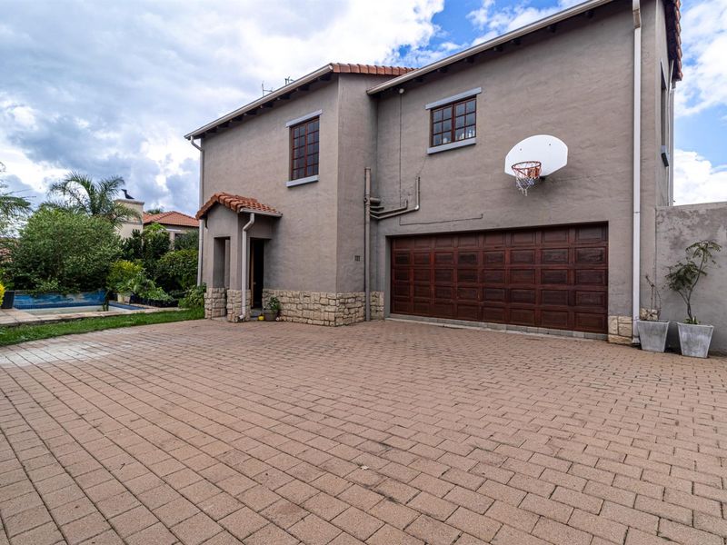 Exterior view of the house featuring a paved driveway, double garage, and side access to the garden area.