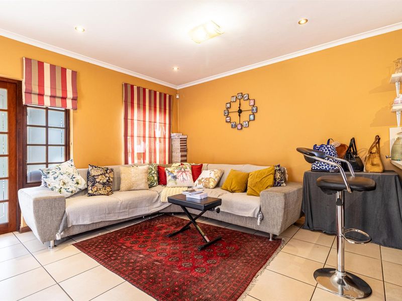 A living area featuring tiled flooring, recessed ceiling lighting, and a glass-paneled door leading to the exterior.