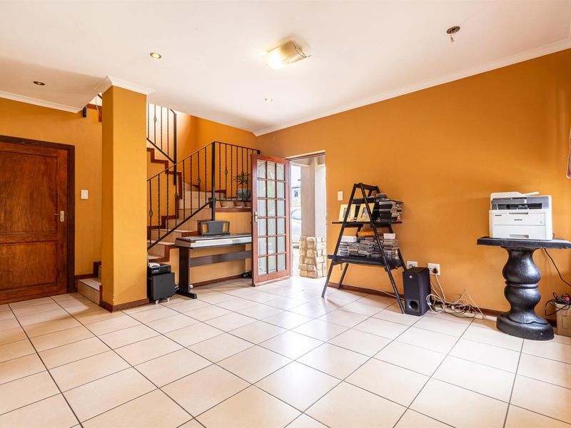 Spacious entry hall featuring tiled flooring, a wooden staircase with metal balustrades, and direct access to the exterior.