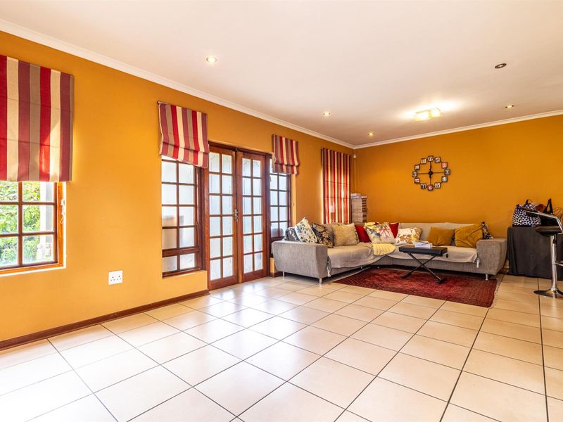Spacious living area featuring tiled flooring, recessed downlighting, and wooden framed glass doors providing access to the exterior.