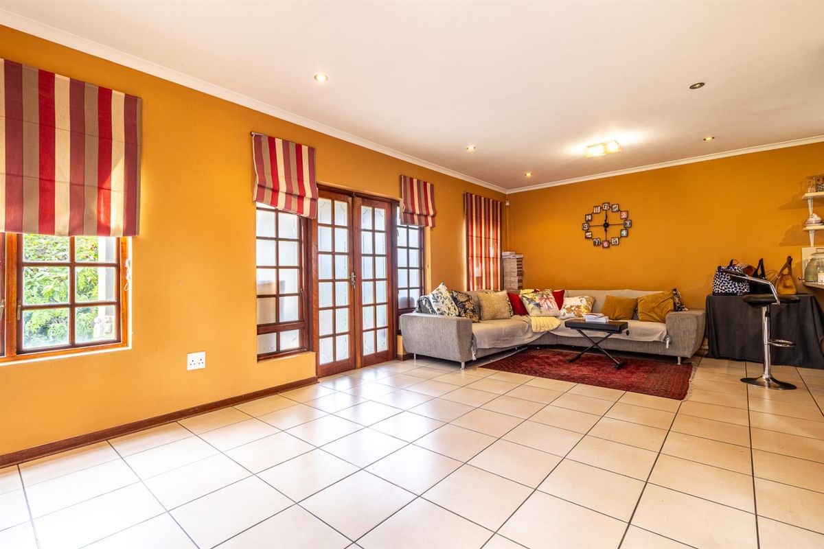 Spacious living area featuring tiled flooring, recessed downlighting, and wooden framed glass doors providing access to the exterior.