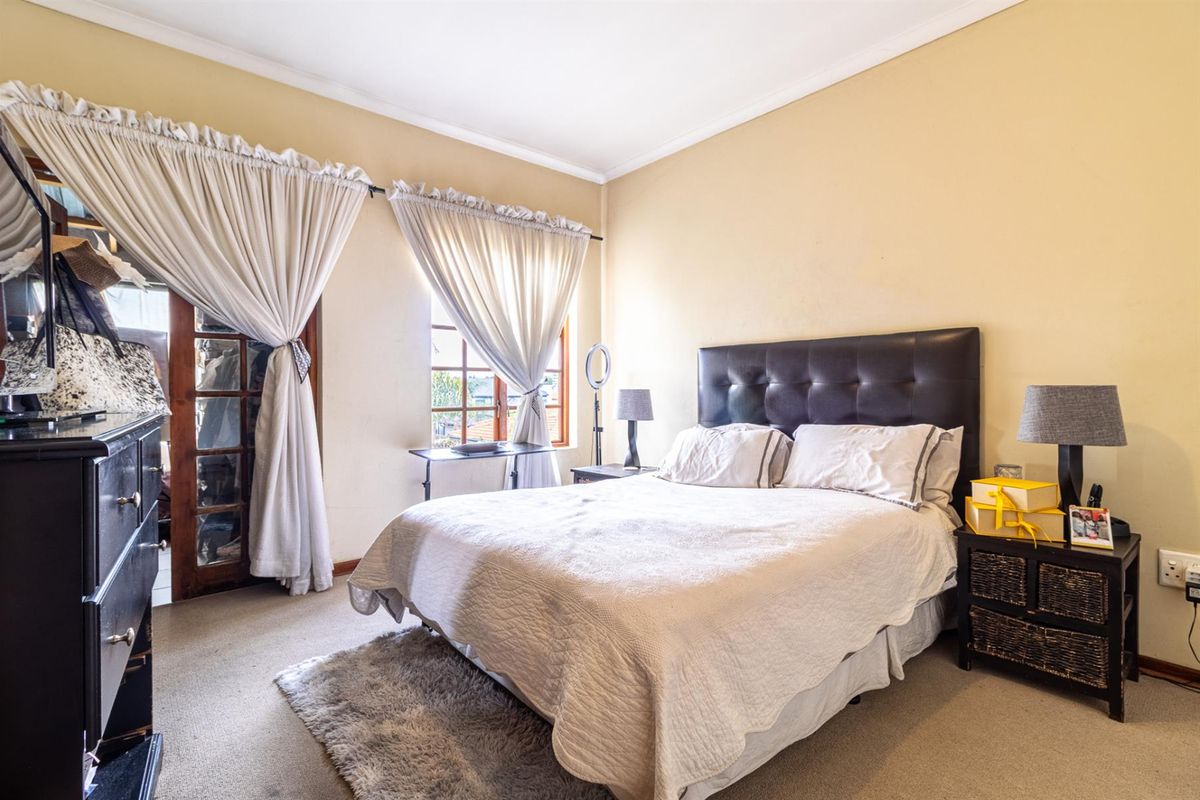 A bedroom featuring timber-framed glass doors leading to an outdoor area and a window with natural light.