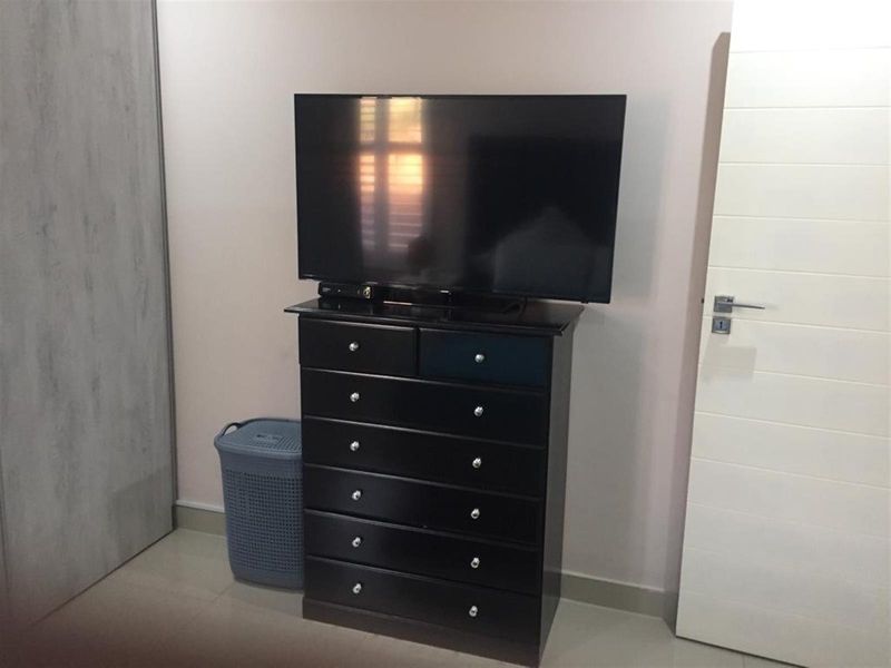 A bedroom interior featuring a built-in wardrobe and a modern internal door with neutral wall finishes.