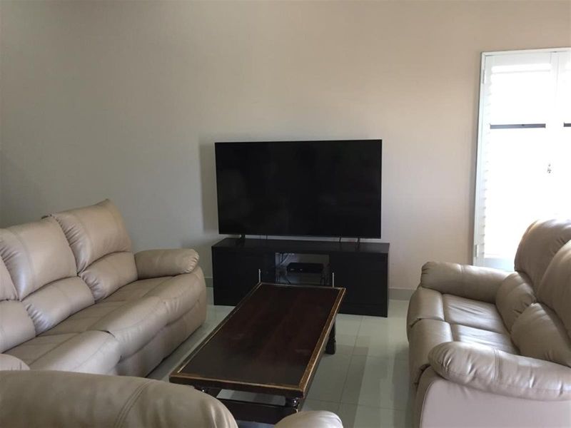 A living room featuring tiled flooring and shutter blinds, providing a neutral space for relaxation.