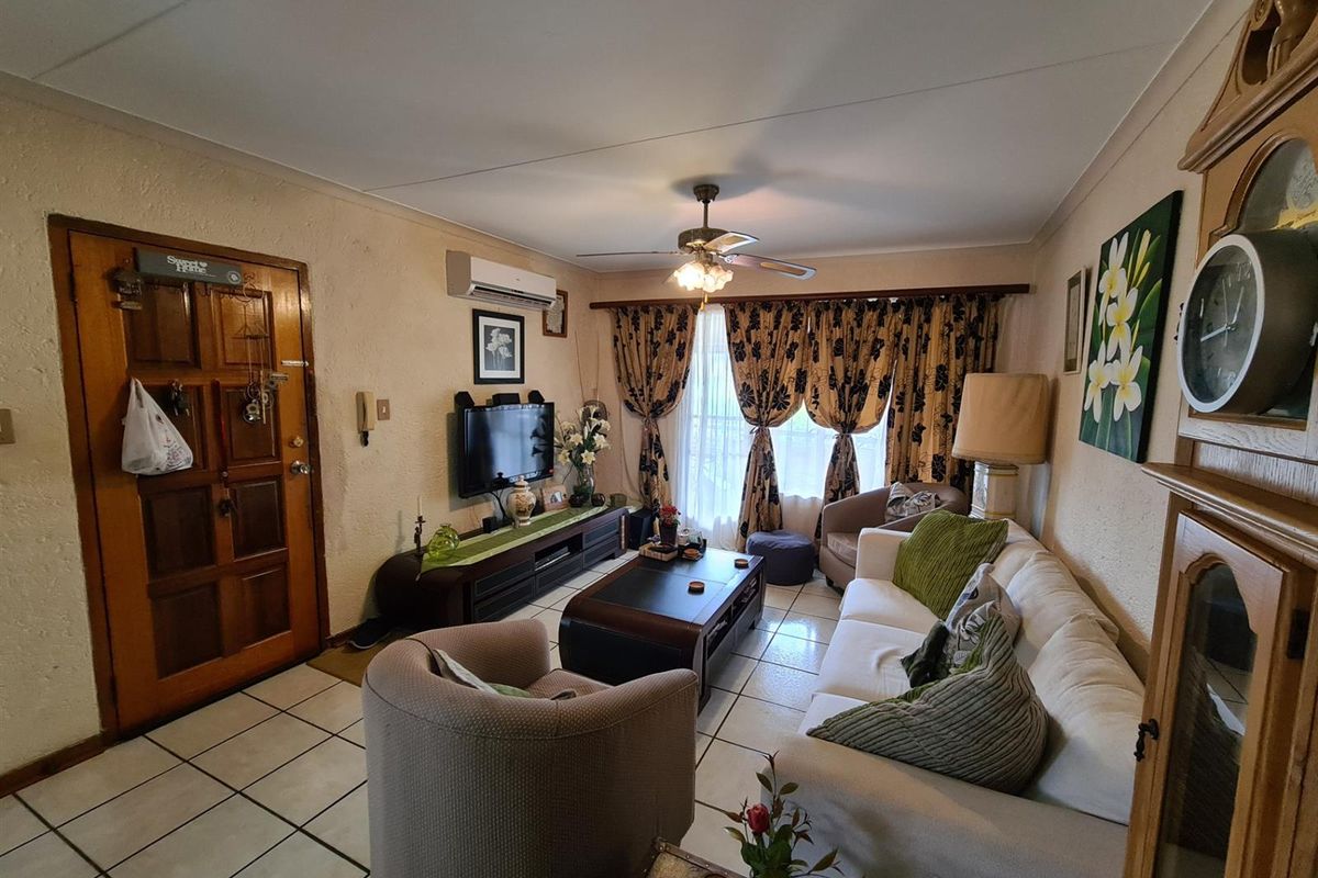 A cozy living room featuring tiled flooring, a ceiling fan, and a wall-mounted air conditioning unit.
