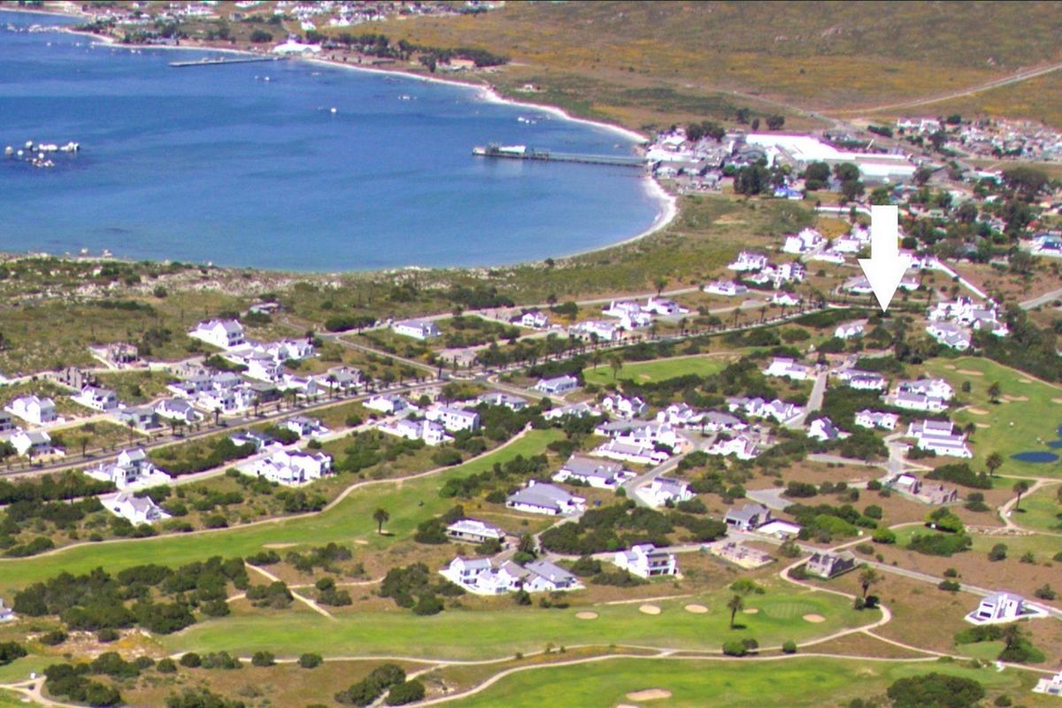 Aerial view of a coastal residential estate featuring a golf course, proximity to the beach, and surrounding natural landscape.