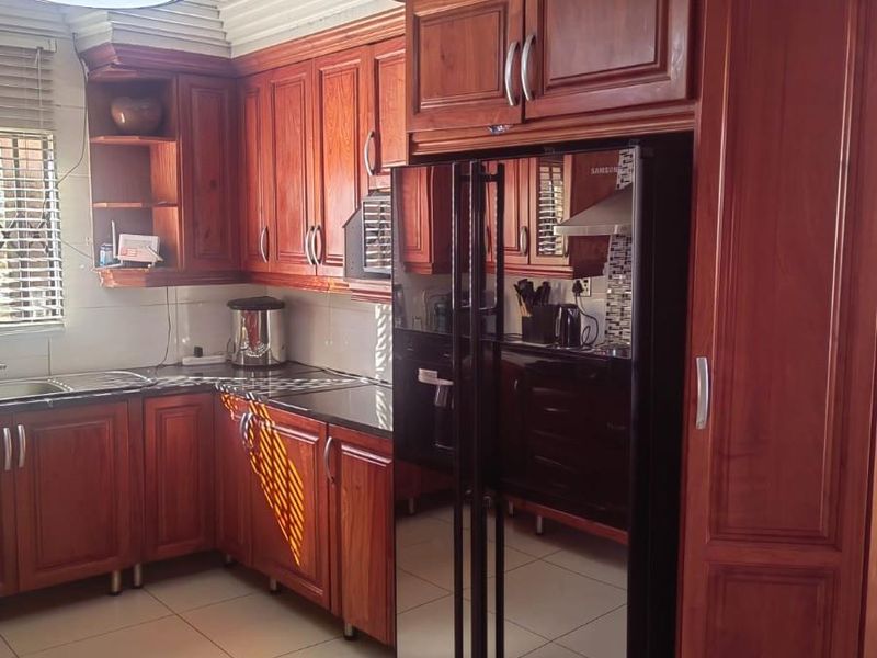 A functional kitchen featuring warm-toned wooden cabinetry, granite countertops, tiled flooring, and a ceiling fan, offering a classic and well-maintained cooking space.