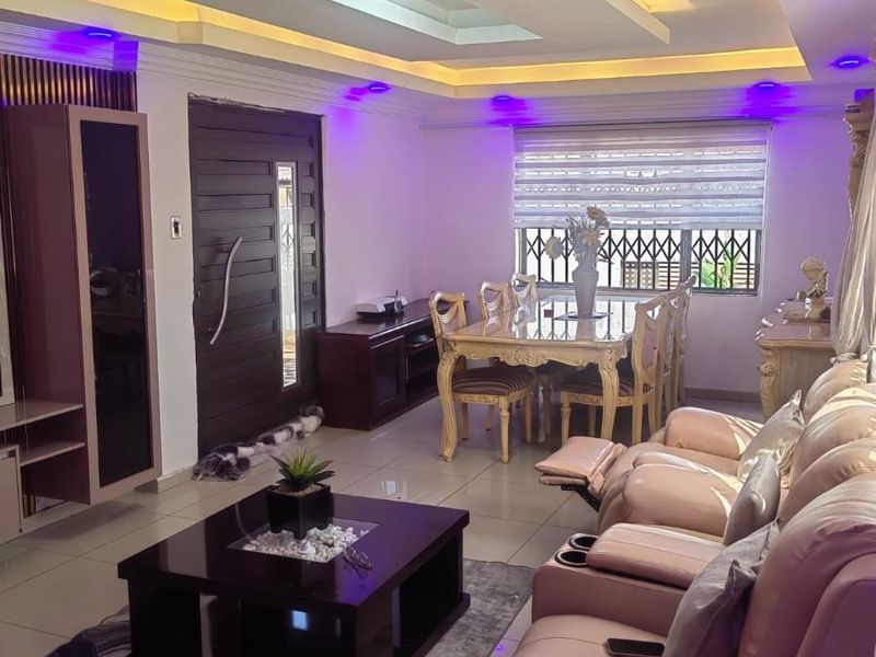 An open-plan living and dining area featuring a modern recessed ceiling with ambient cove lighting and large format floor tiles.
