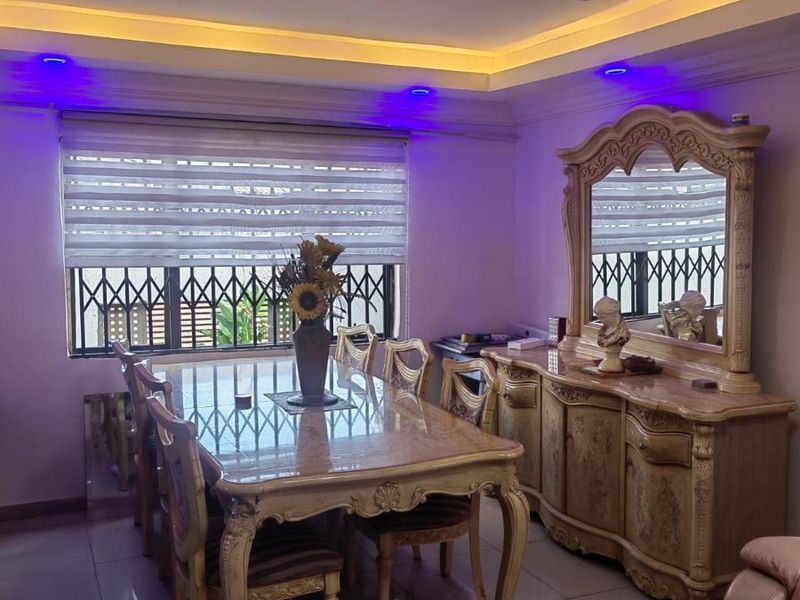 A formal dining room featuring tiled flooring, a recessed ceiling with cove lighting, and security bars on the window.