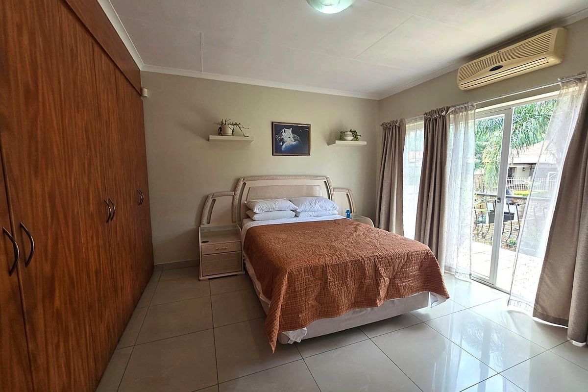 A bedroom featuring built-in wooden cupboards, tiled flooring, and sliding glass doors providing access to the outdoor area.