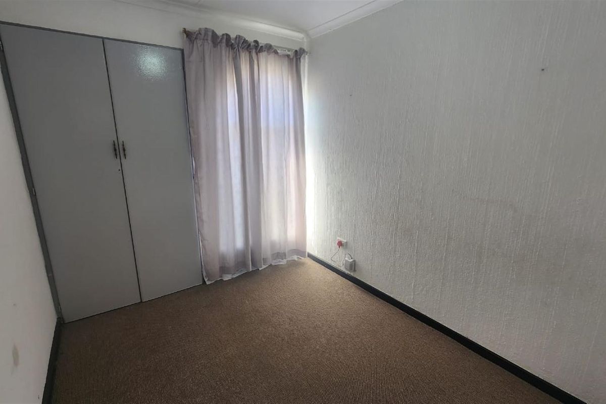 A compact, empty bedroom featuring built-in cupboards, carpeted flooring, and neutral wall finishes, offering a blank canvas for potential updates.