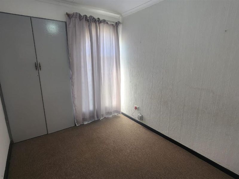 A compact, empty bedroom featuring built-in cupboards, carpeted flooring, and neutral wall finishes, offering a blank canvas for potential updates.
