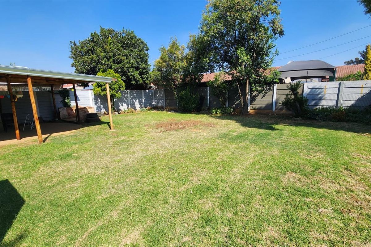 Spacious rear garden featuring a covered patio area and secure precast concrete boundary walls.