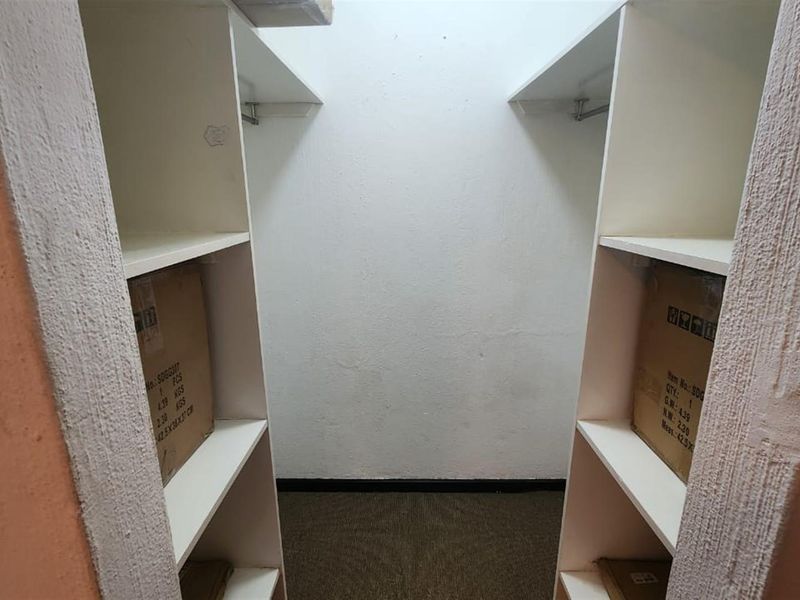 A small utility or storage space featuring built-in shelving units and carpeted flooring, suitable for organization or walk-in storage.
