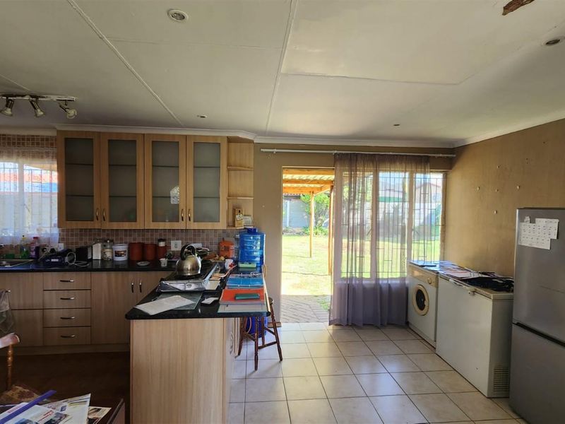 Kitchen featuring built-in cabinetry, granite countertops, and tiled flooring with direct access to the rear garden area.