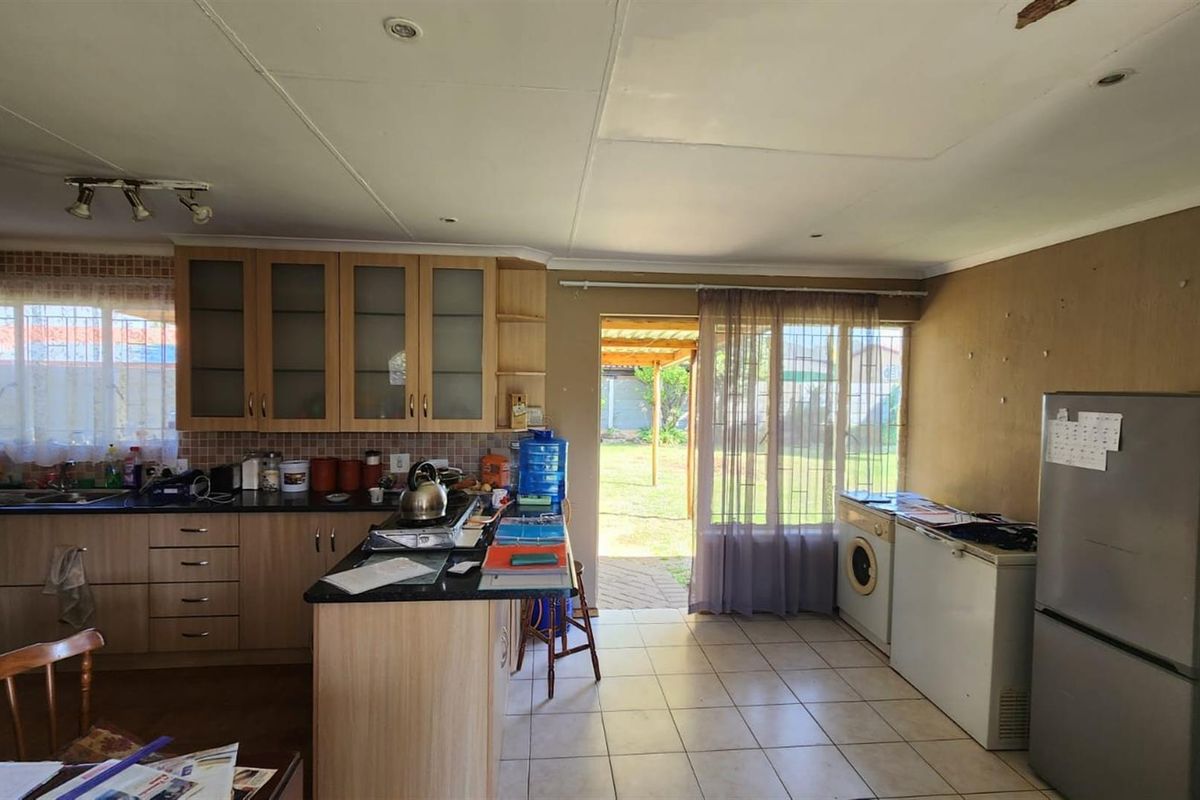Kitchen featuring built-in cabinetry, granite countertops, and tiled flooring with direct access to the rear garden area.