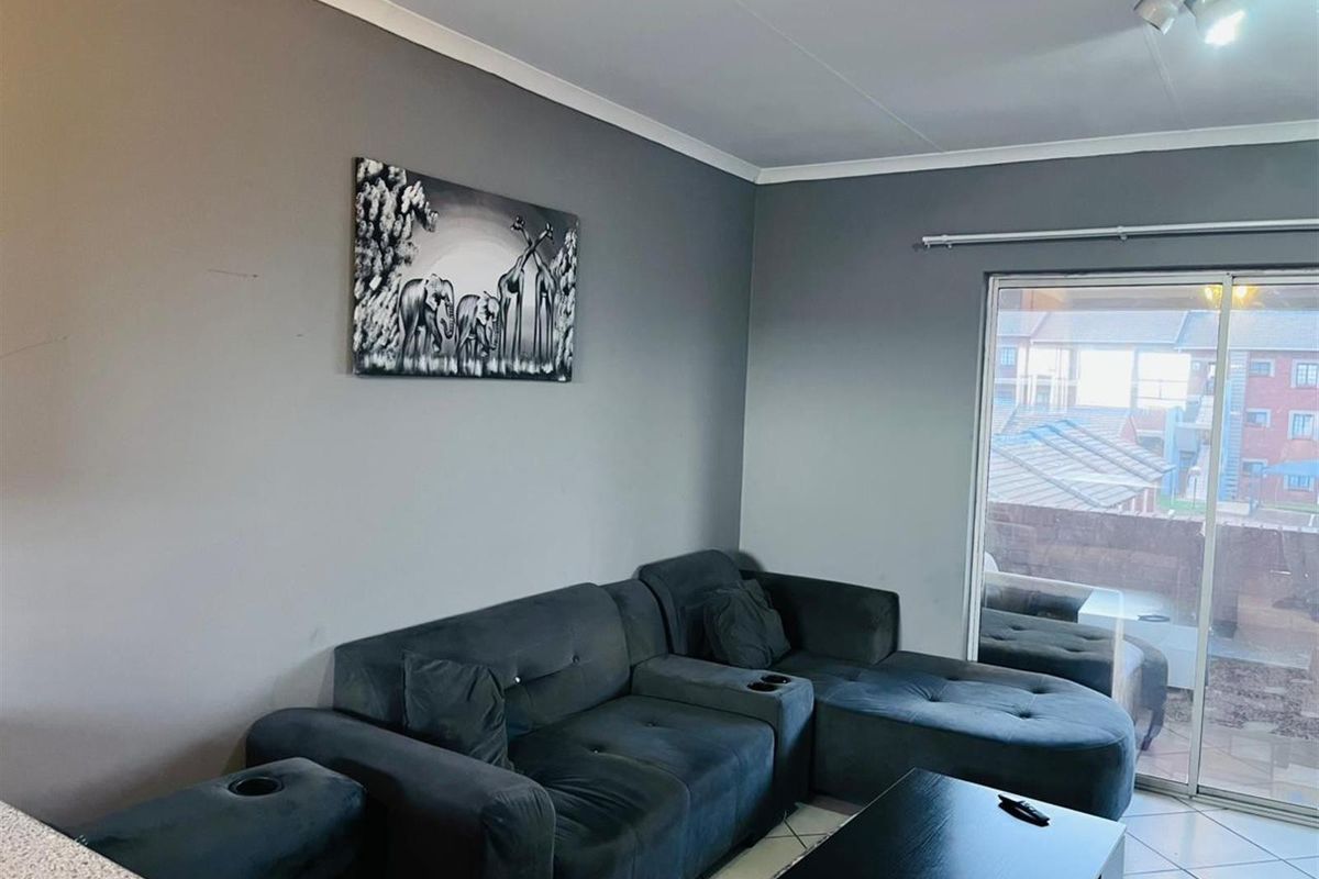 A living room featuring tiled flooring and a sliding glass door providing access to an outdoor balcony area.