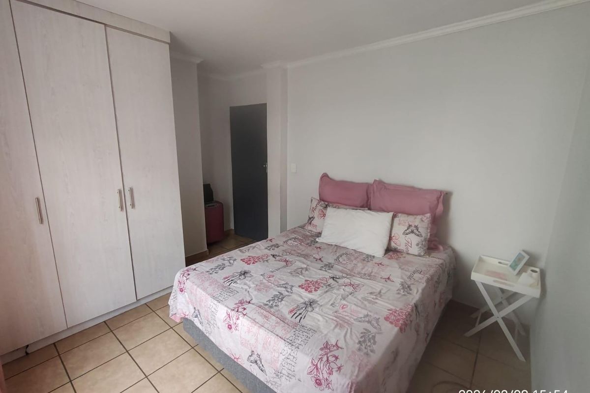 A bedroom featuring built-in cupboards with light wood-grain finish and tiled flooring.