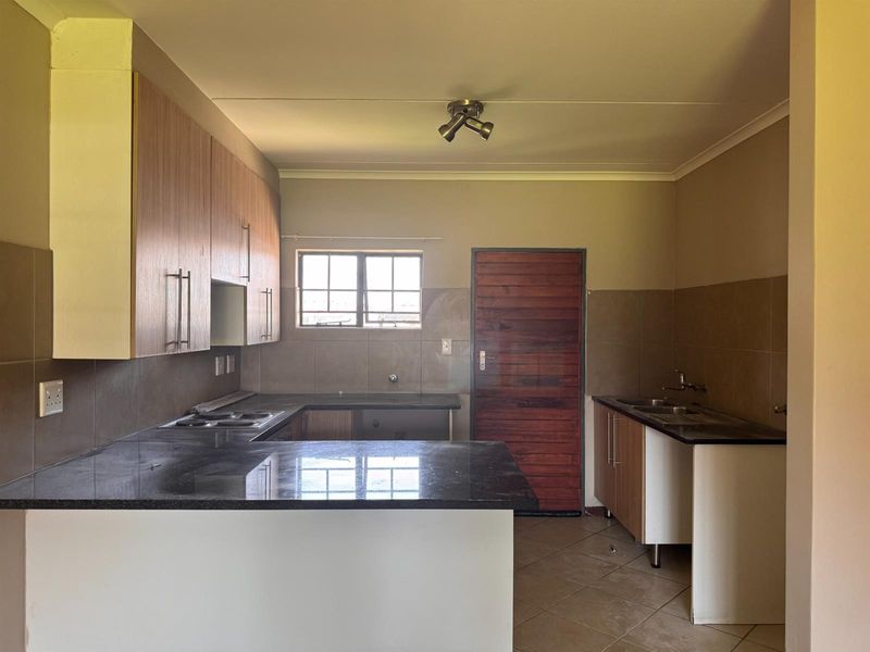 A functional kitchen featuring granite countertops, built-in cabinetry, a double sink, and a tiled backsplash, offering a clean and practical layout.