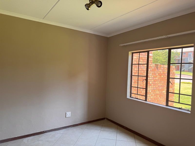 An empty bedroom featuring tiled flooring, a steel-framed window with a curtain rail, and neutral wall tones, ready for personalization.