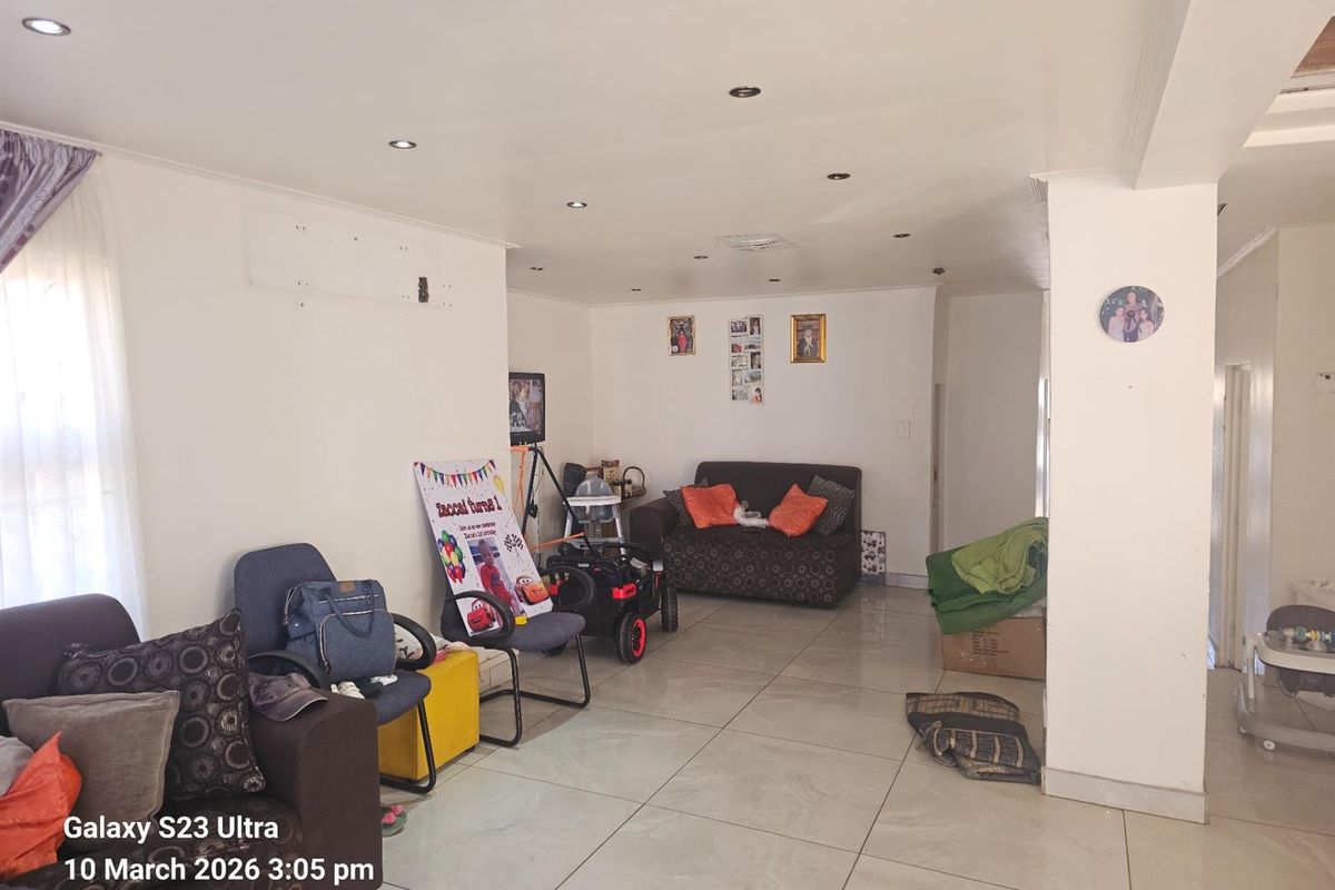 Spacious living area featuring large format floor tiles and recessed downlighting, offering a neutral base for potential interior design updates.