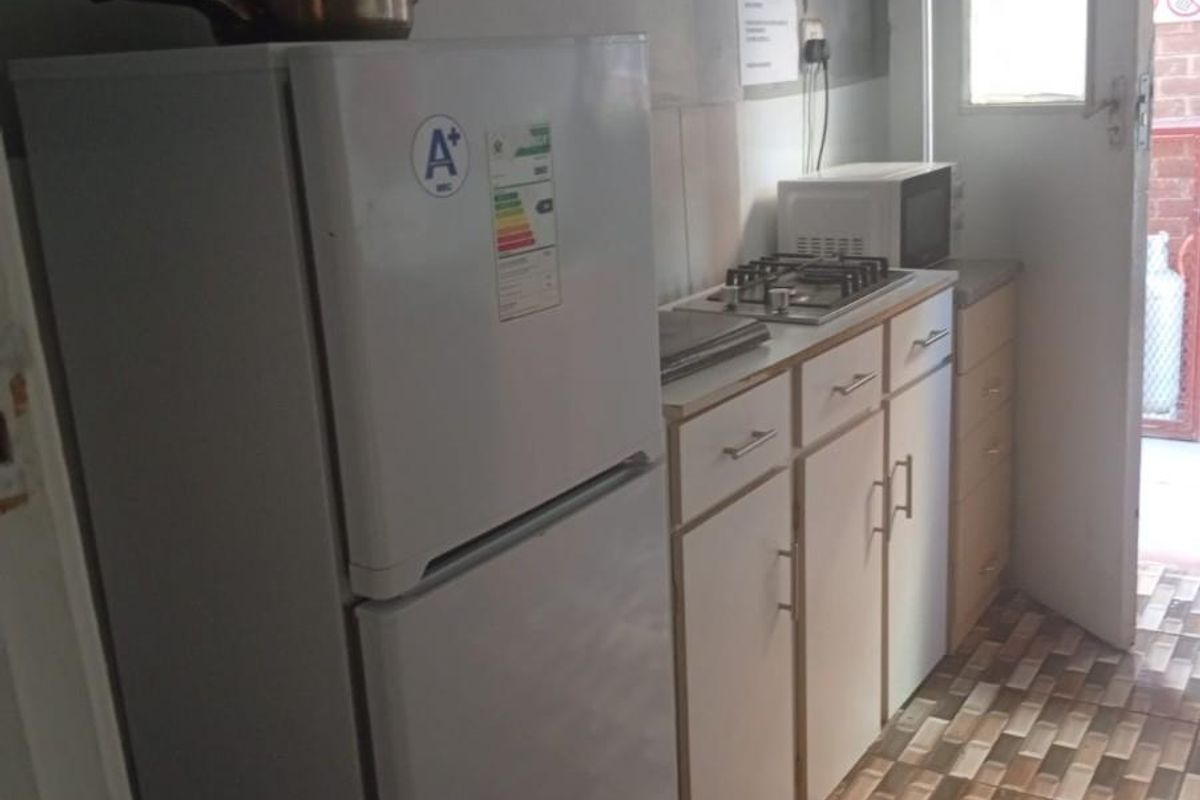 A compact kitchen area featuring built-in cabinetry, a gas hob, and tiled flooring with direct access to an exterior door.
