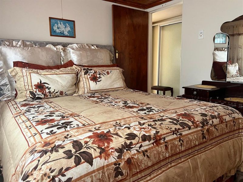 A bedroom featuring a timber ceiling and a sliding door leading to an adjacent space, offering a functional layout with traditional finishes.