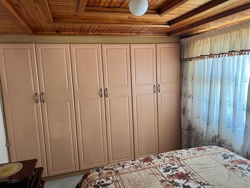 Bedroom featuring extensive built-in cabinetry and a traditional timber panelled ceiling.