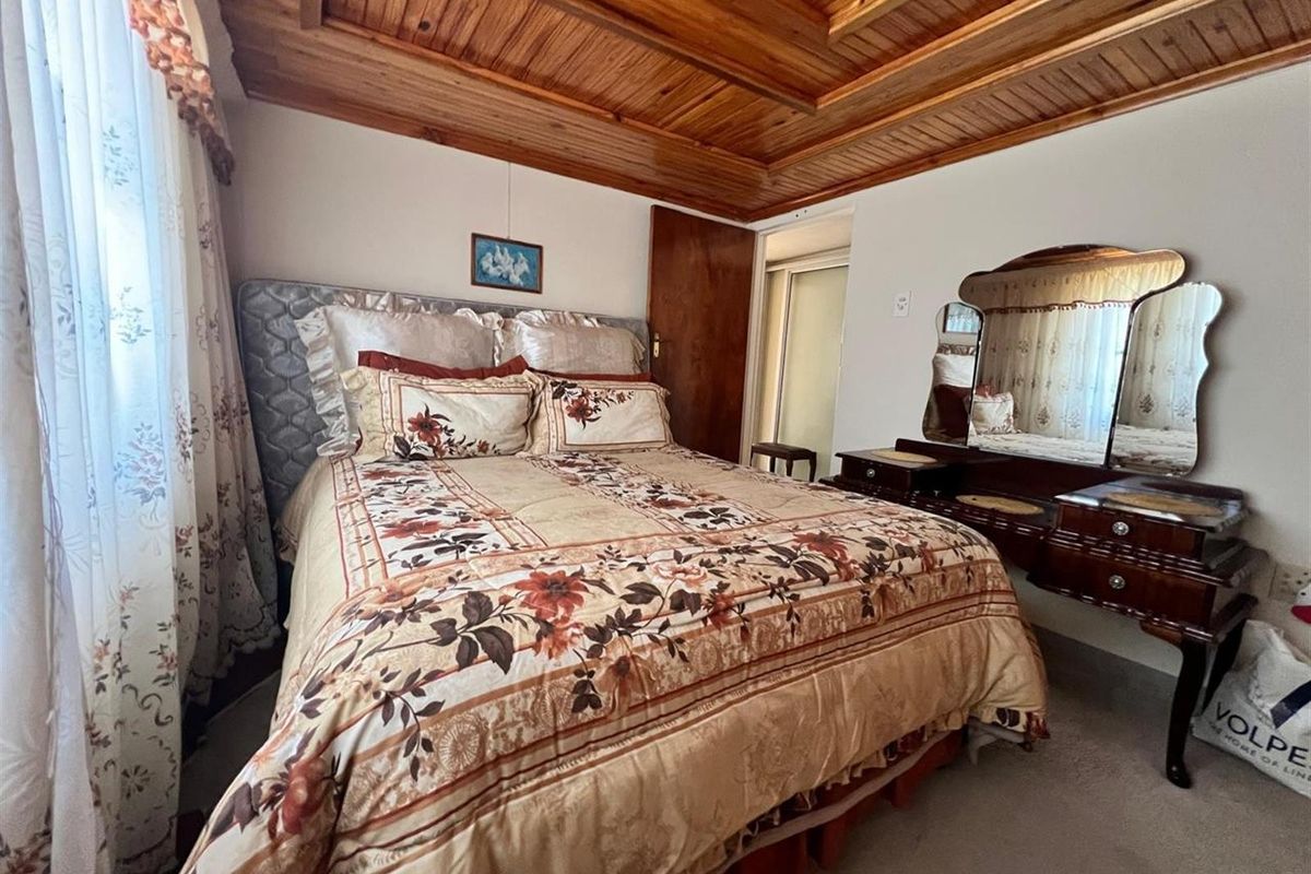 A bedroom featuring a distinctive timber tongue and groove ceiling and built-in storage.