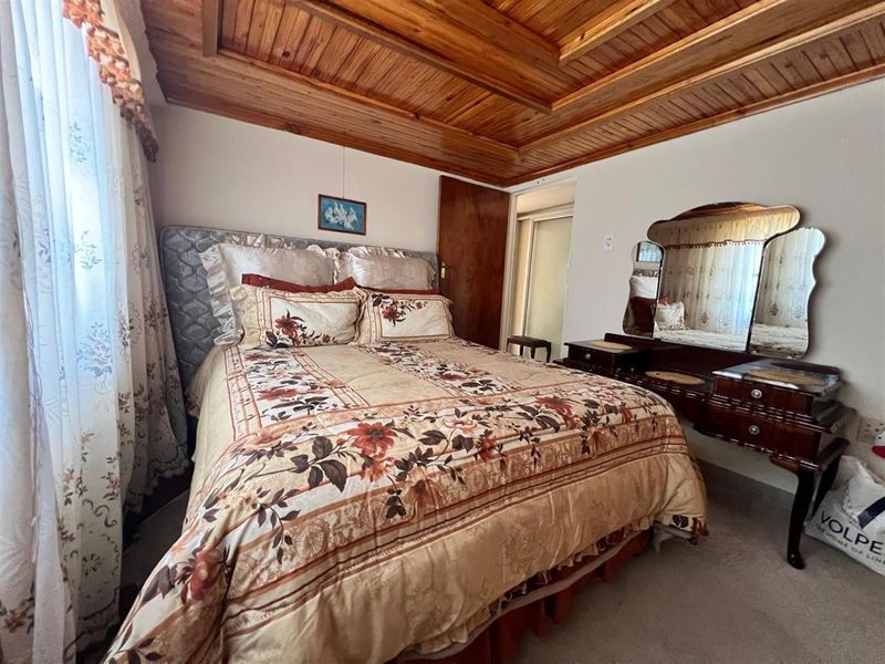 A bedroom featuring a distinctive timber tongue and groove ceiling and built-in storage.