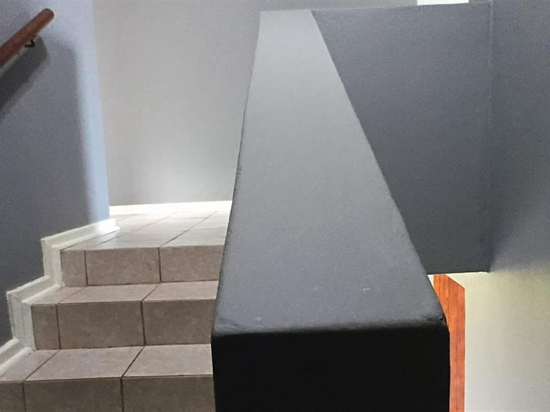 A staircase featuring tiled steps, a solid balustrade, and a wooden handrail, providing access between levels.