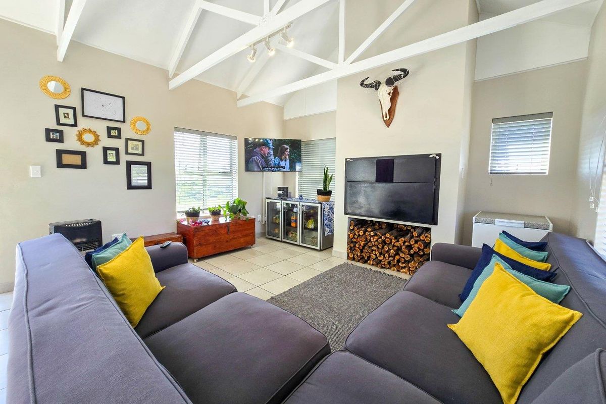 Spacious living room featuring high vaulted ceilings with exposed white trusses, tiled flooring, and a built-in fireplace with integrated log storage.